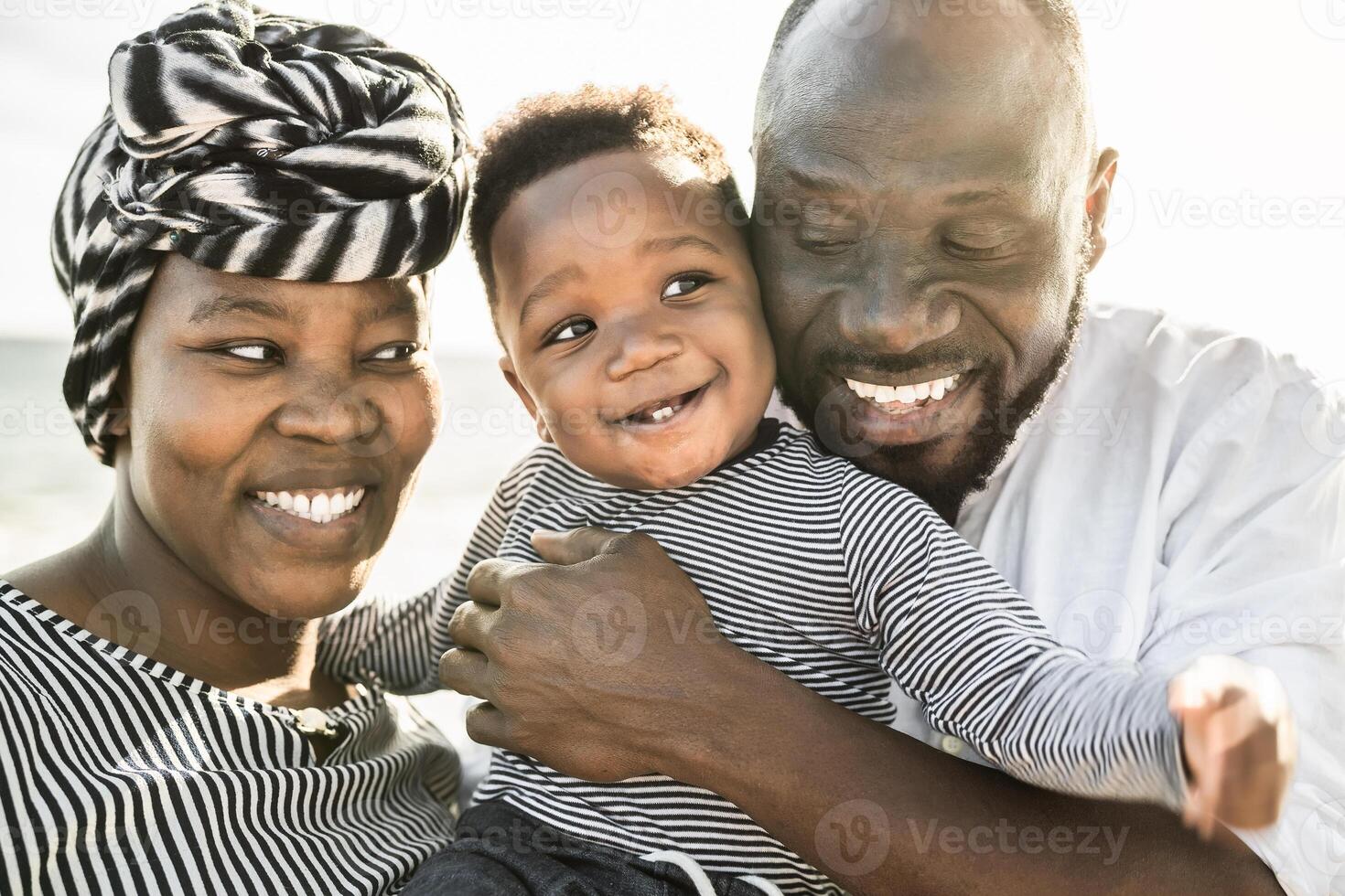 Happy African family having fun on the beach during summer holidays - Parents love concep photo