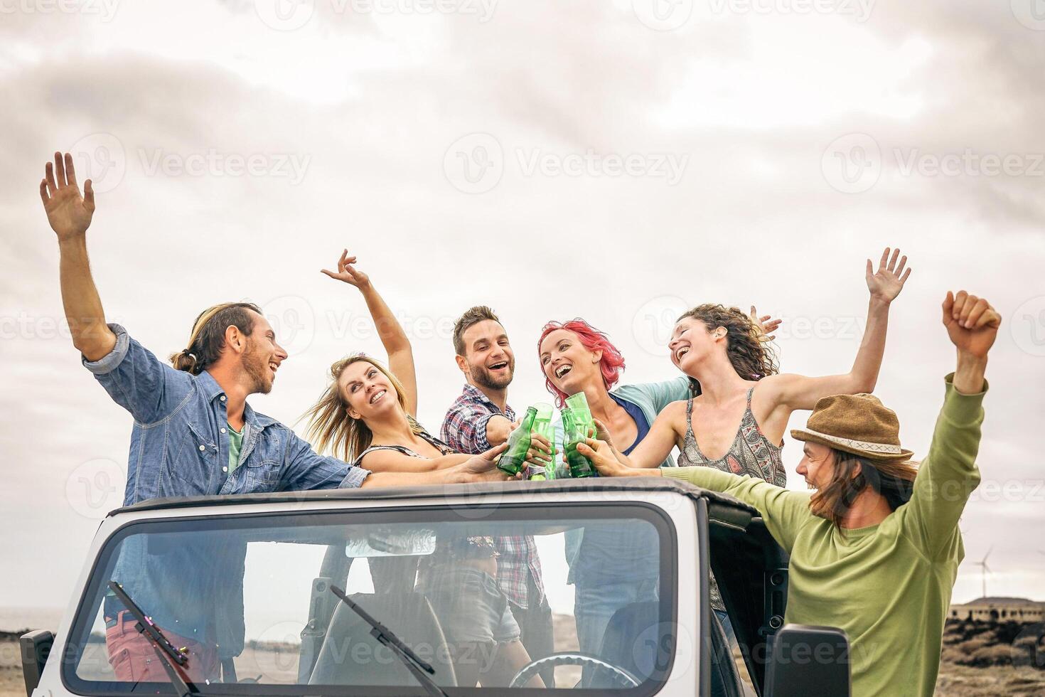 grupo de contento amigos aplausos con cerveza en convertible coche - joven personas teniendo divertido Bebiendo y haciendo fiesta durante su la carretera viaje - amistad, vacaciones, juventud Días festivos estilo de vida concepto foto