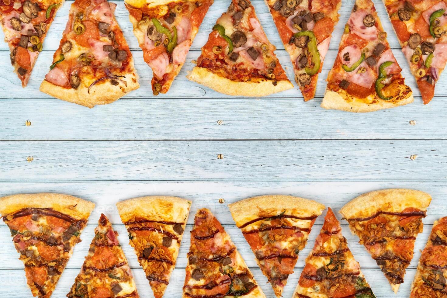 Lots of delicious triangular pizza slices on a blue wooden background photo