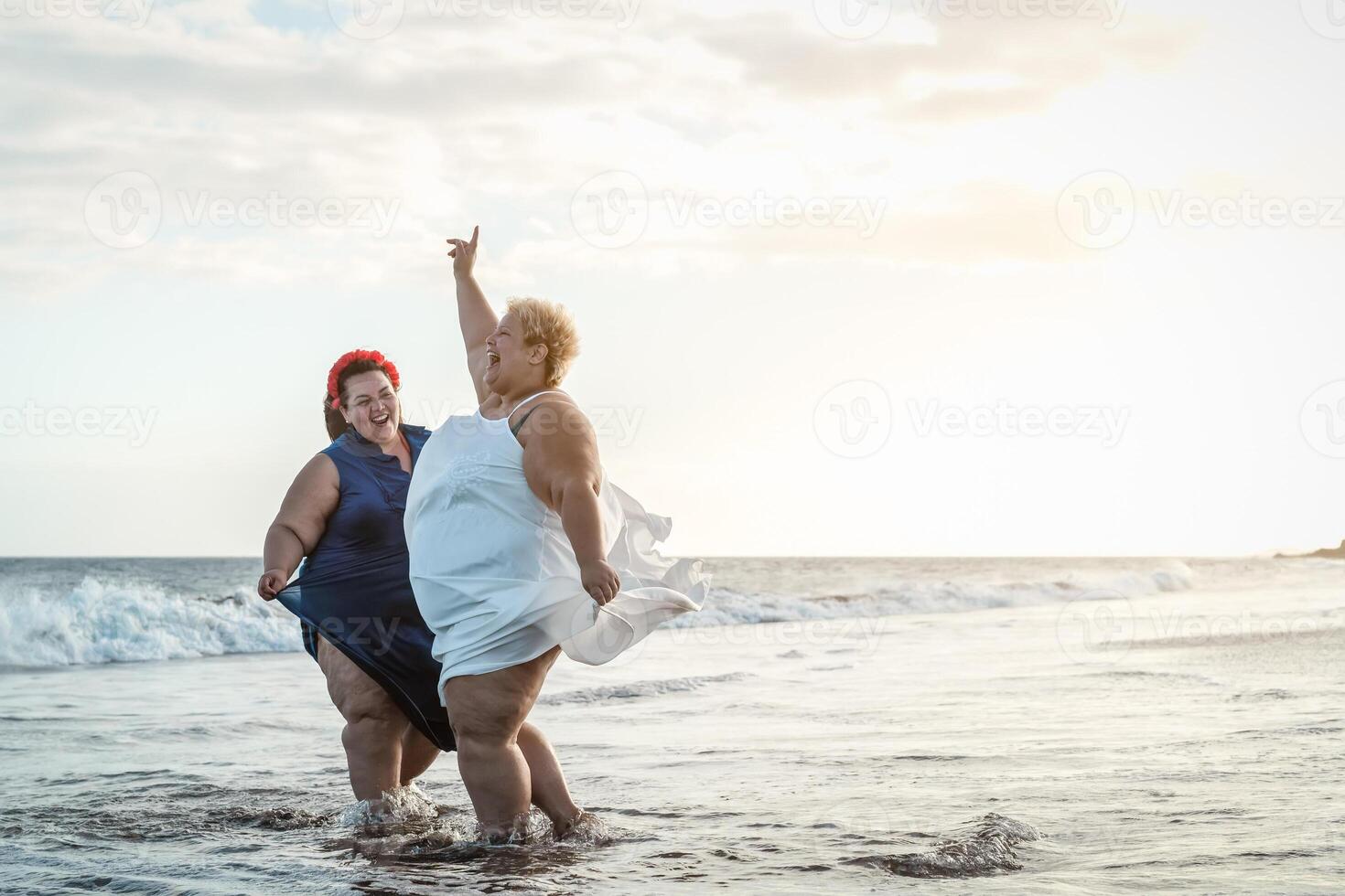 Happy plus size women having fun on the beach during summer vacation - Curvy confident people lifestyle concept photo