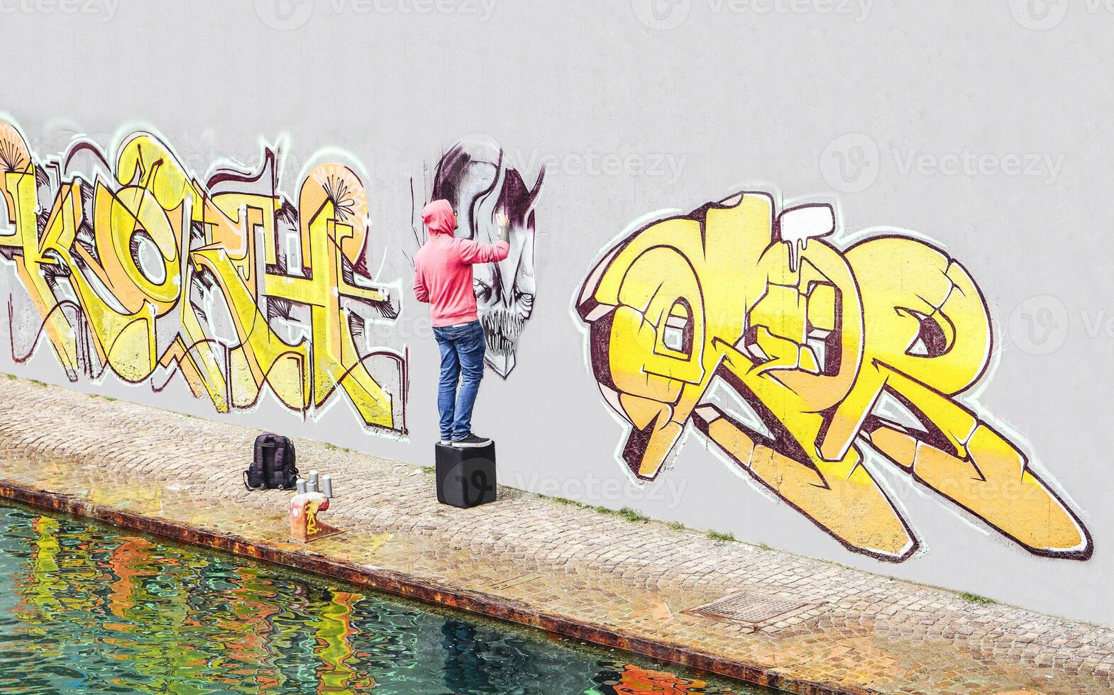 Street graffiti artist painting with a color spray can a graffiti on the wall in the city - Concept of contemporary art lifestyle photo