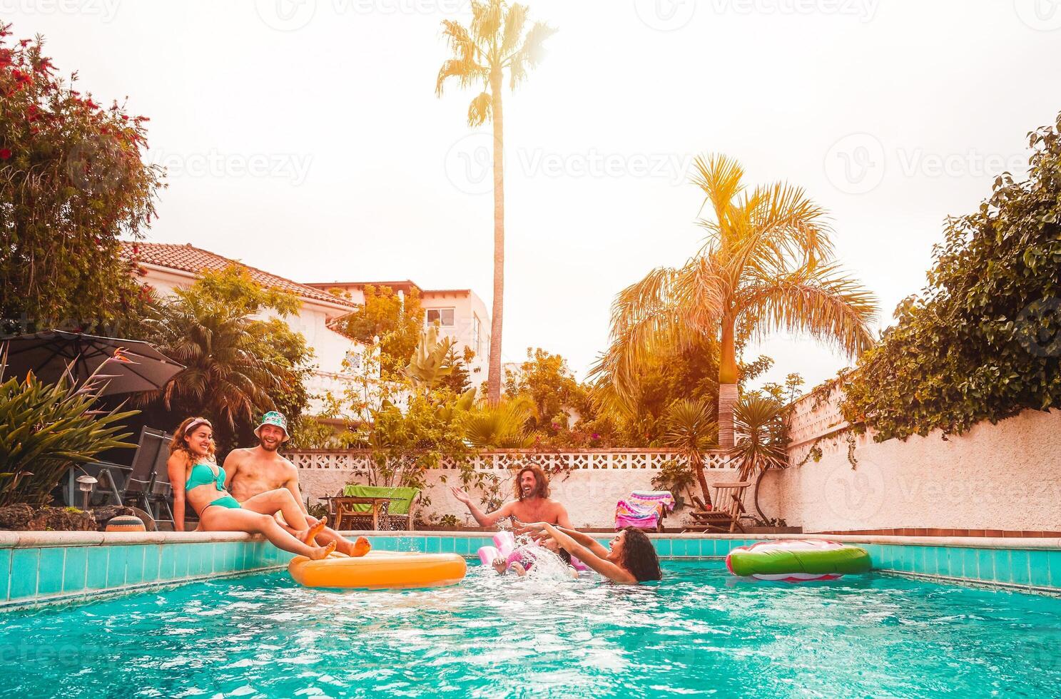 grupo de contento amigos relajante en nadando piscina - joven personas teniendo divertido flotante en aire lilo durante verano tropical vacaciones - amistad, Días festivos y juventud estilo de vida concepto foto