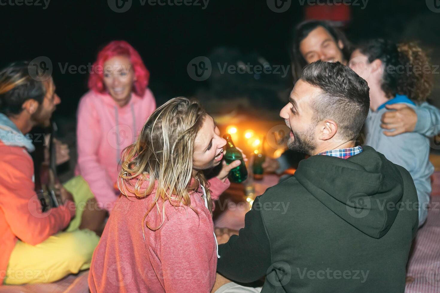 grupo de amigos cámping en el playa durante el noche - joven milenario personas teniendo divertido haciendo parilla Bebiendo cerveza y jugando guitarra - amistad, fiesta y juventud estilo de vida Días festivos foto