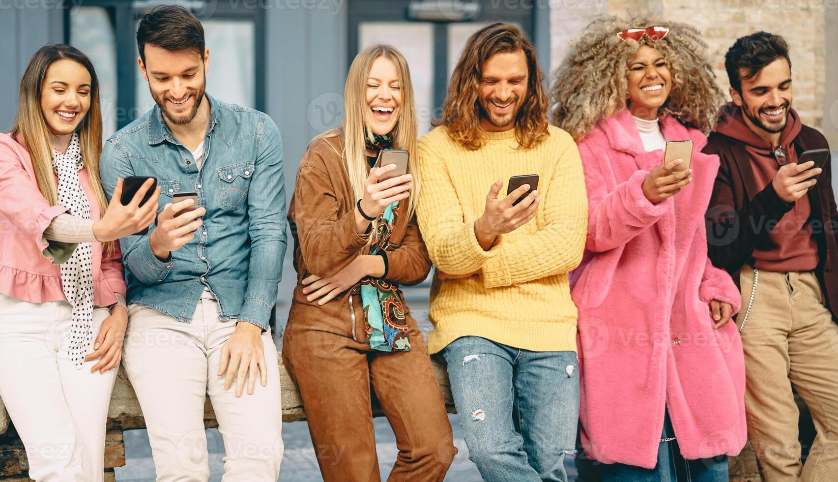 Group of trendy friends using mobile smartphones outdoor - Millennial young people having fun with new technology apps for social media - Concept of youth culture generation z and technology photo
