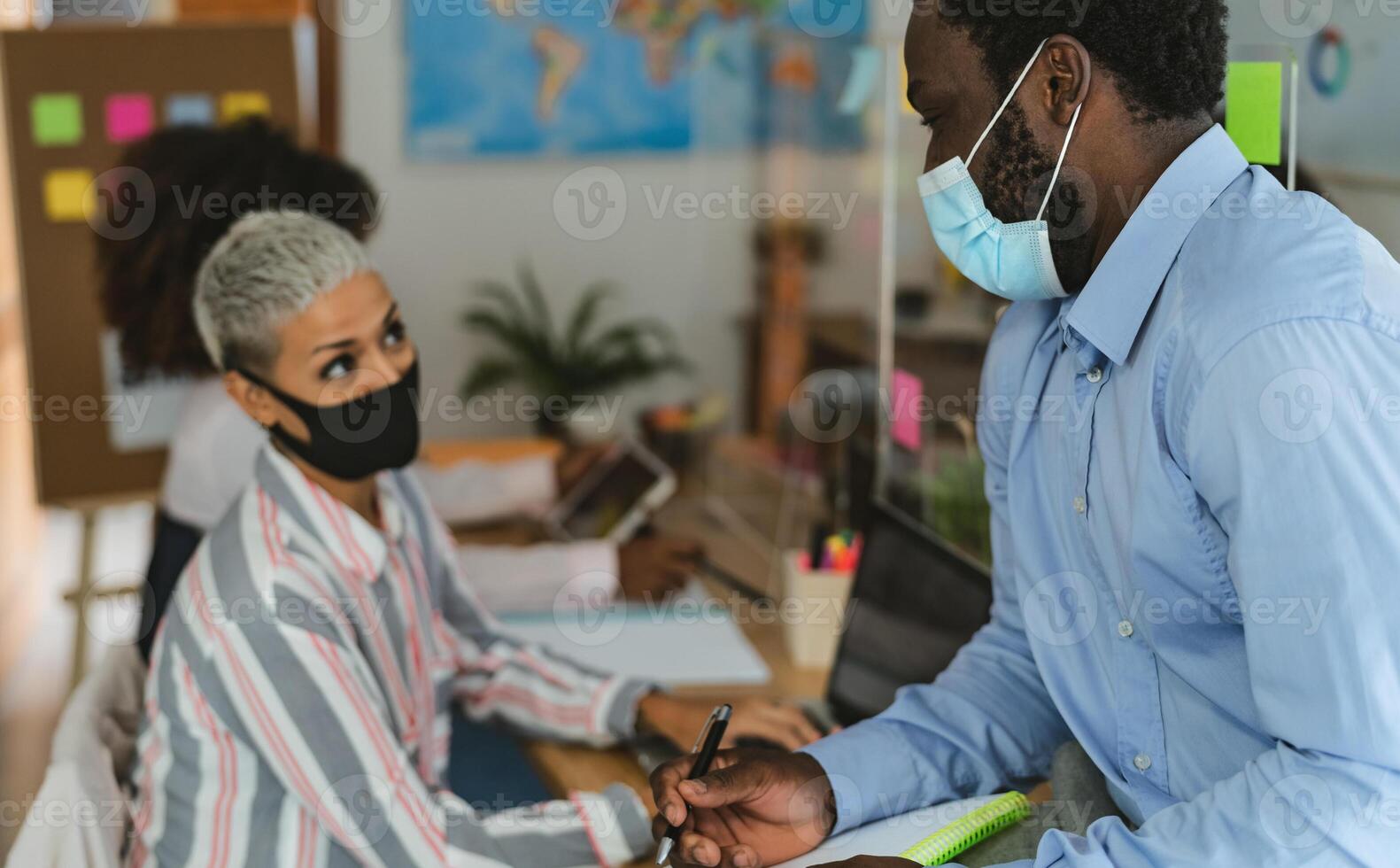 Young people in co-working creative space wearing surgical mask and keeping social distance to avoid corona virus spread - Health care and business technology concept photo