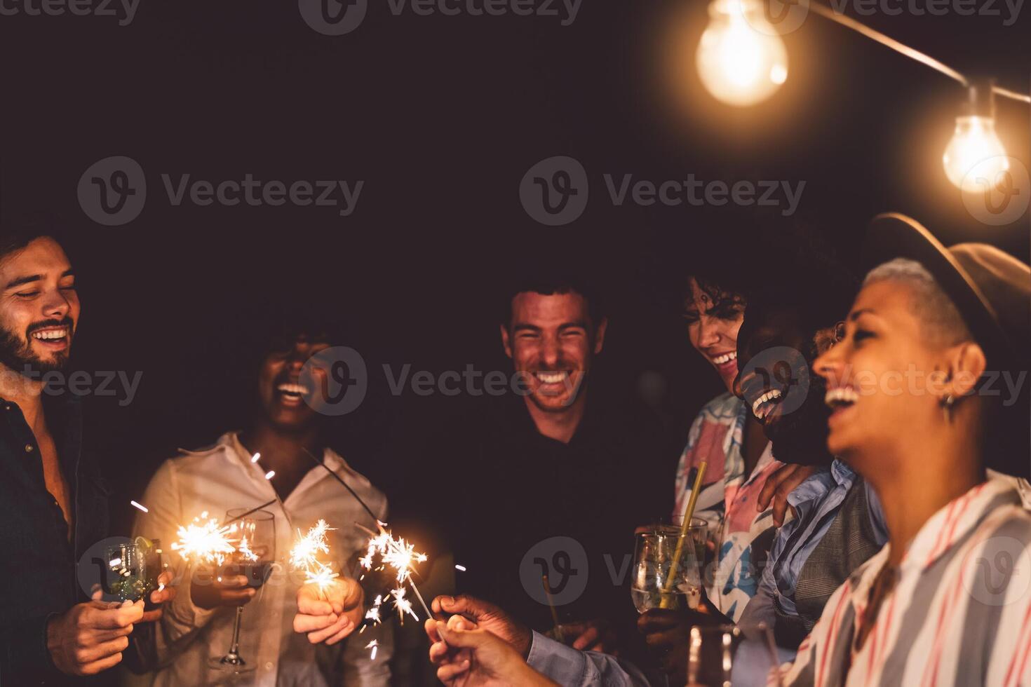 contento joven amigos celebrando nuevo año víspera con bengalas fuegos artificiales y Bebiendo cócteles en patio casa fiesta - juventud personas estilo de vida y Días festivos concepto foto