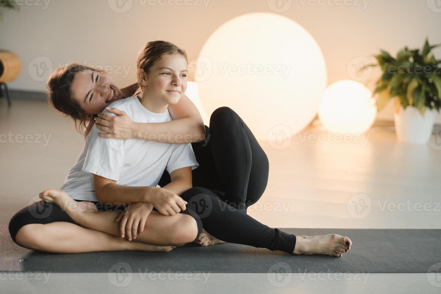 portrait of a mother and daughter of a teenager in sports clothes hugging, who are together in a fitness room. the concept of family sports photo