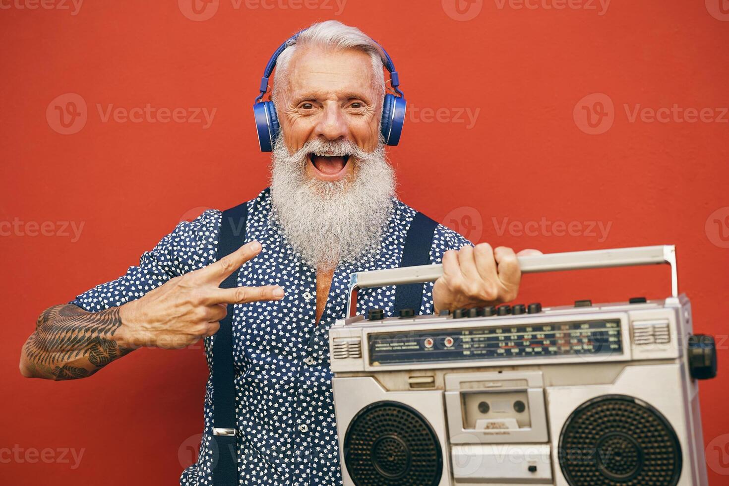 Happy senior man listening to music with wireless headphones and vintage boombox outdoor photo