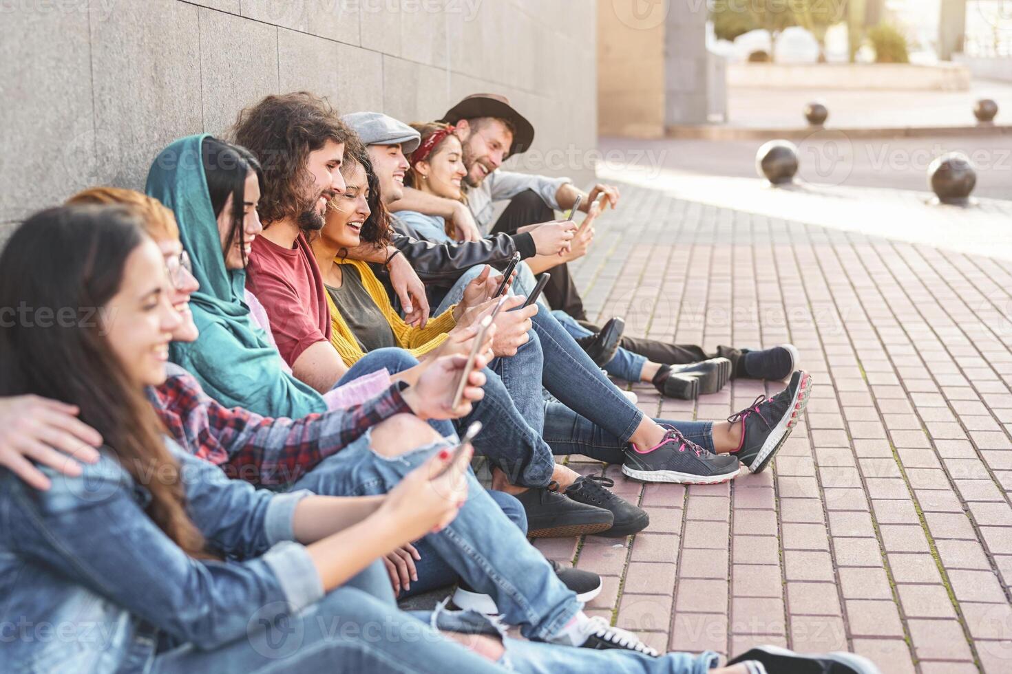 Group trendy friends using smart mobile phones outdoor - Millennial people having fun with new technology trends smartphone - Youth generation lifestyle and tech addiction social media concept photo