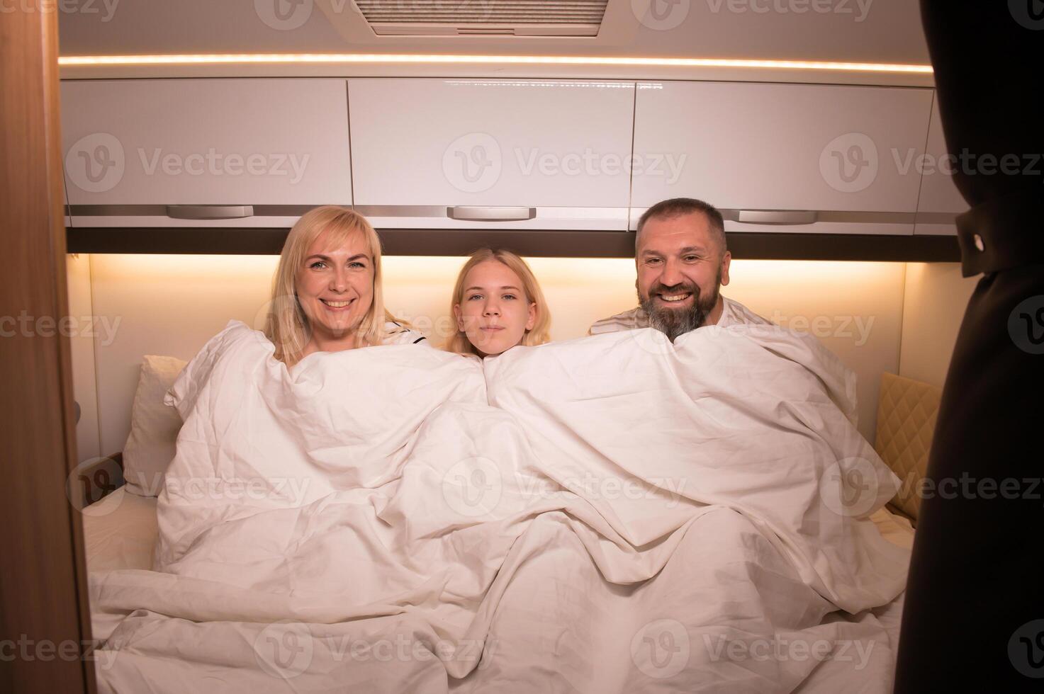 The family is getting ready for bed sitting on the bed in their motorhome photo