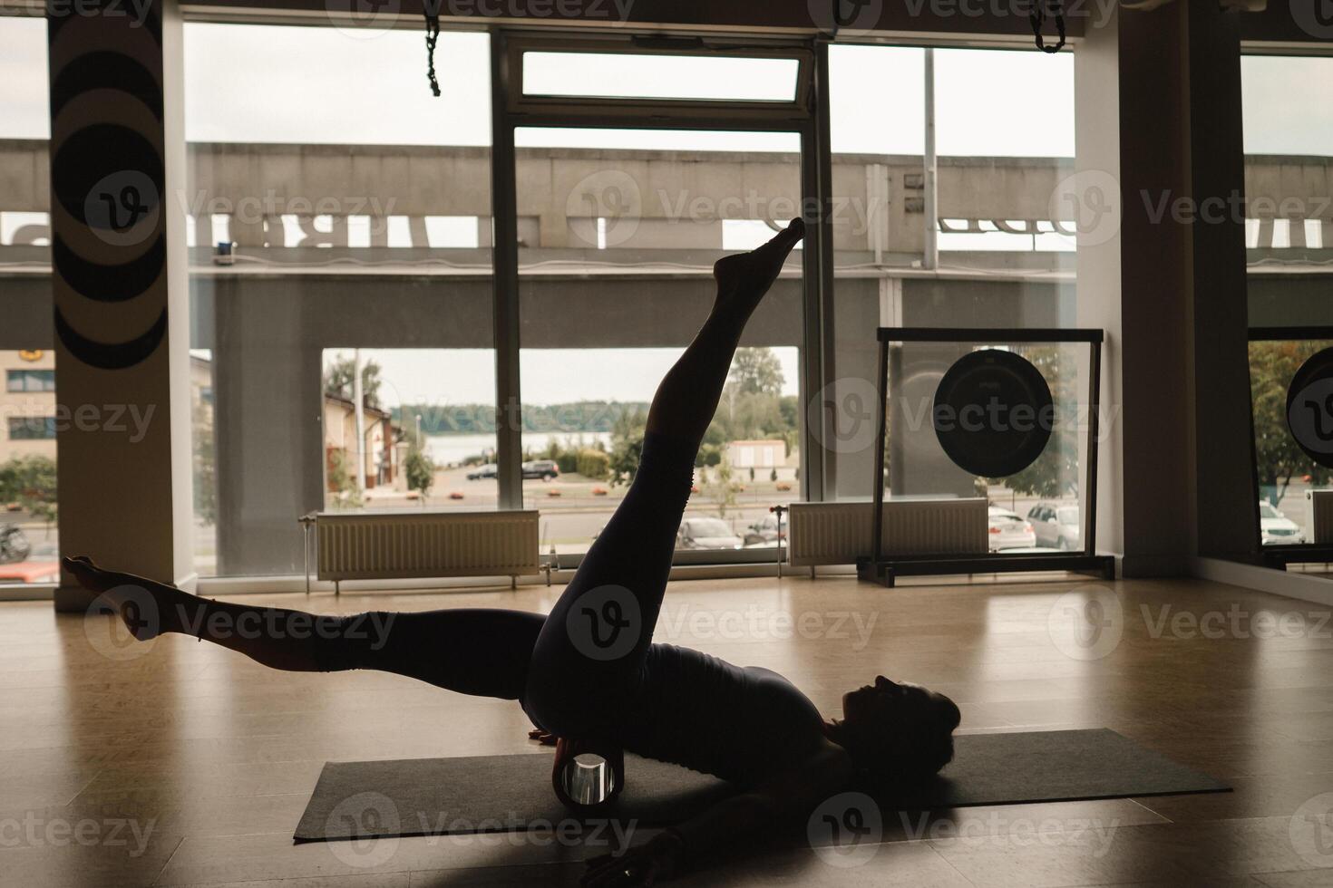 esbelto niña haciendo yoga con un grande masaje rodillo en el piso foto