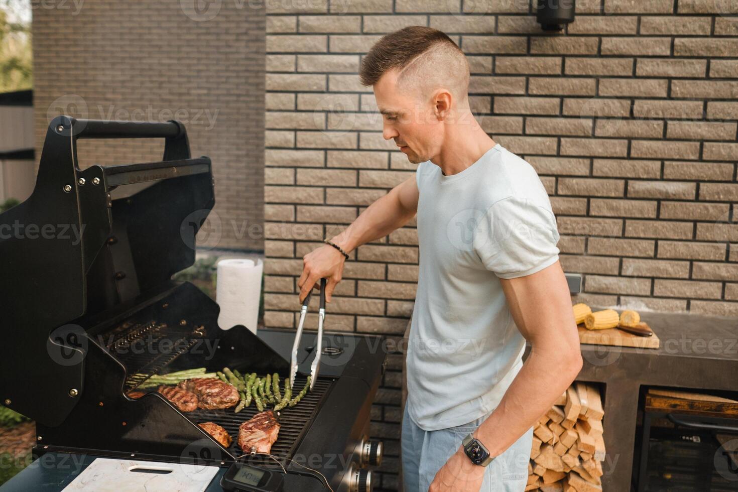 A man on the street is cooking a steak on the grill at a barbecue photo