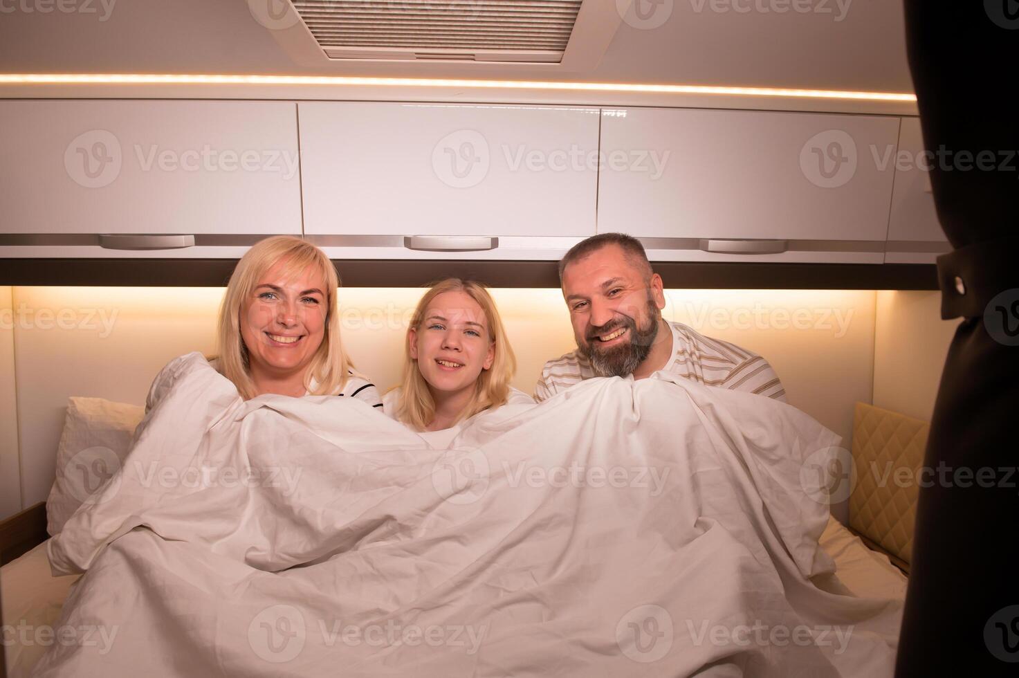 The family is getting ready for bed sitting on the bed in their motorhome photo