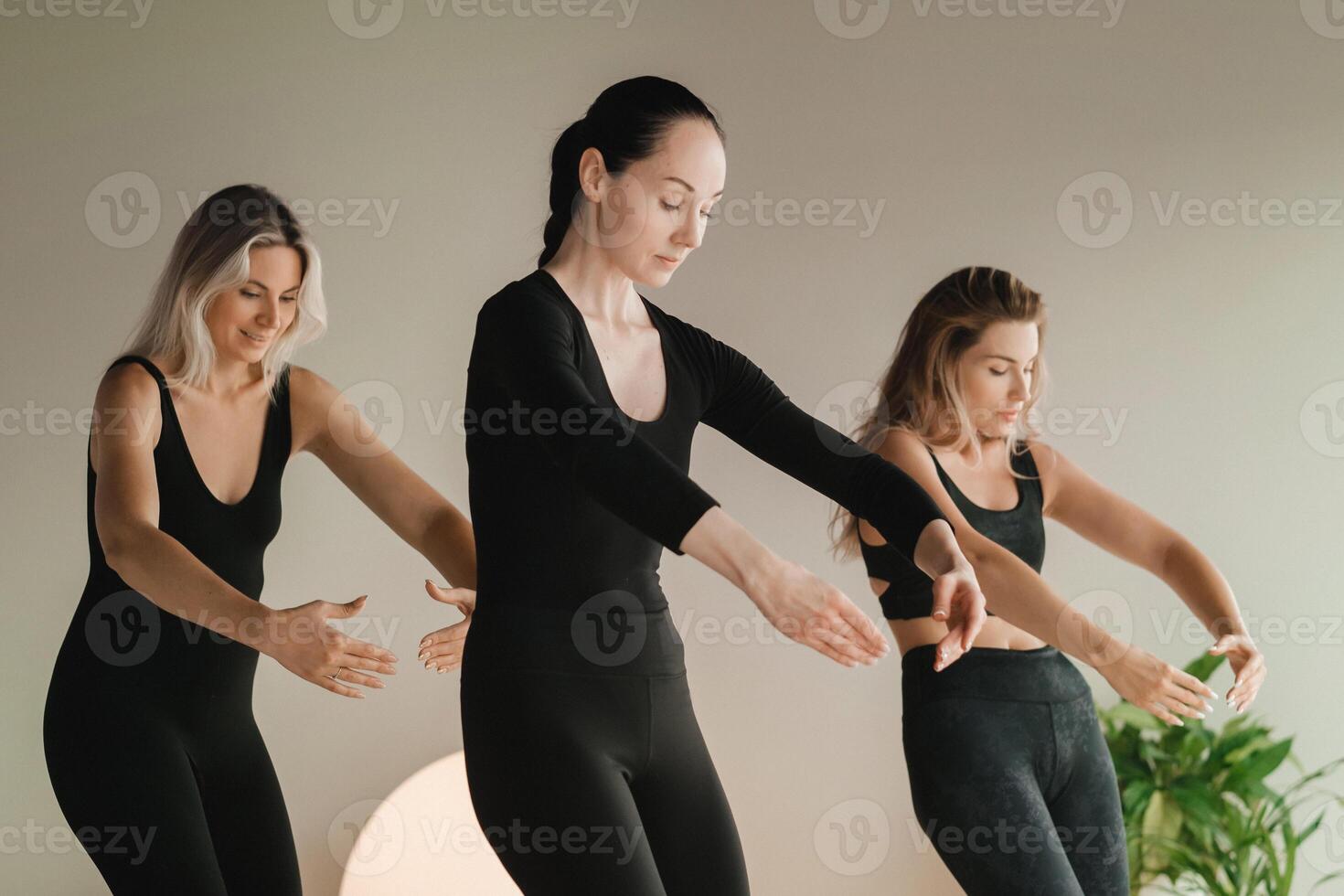 A group of girls in black doing yoga poses indoors. Women are engaged in fitness photo
