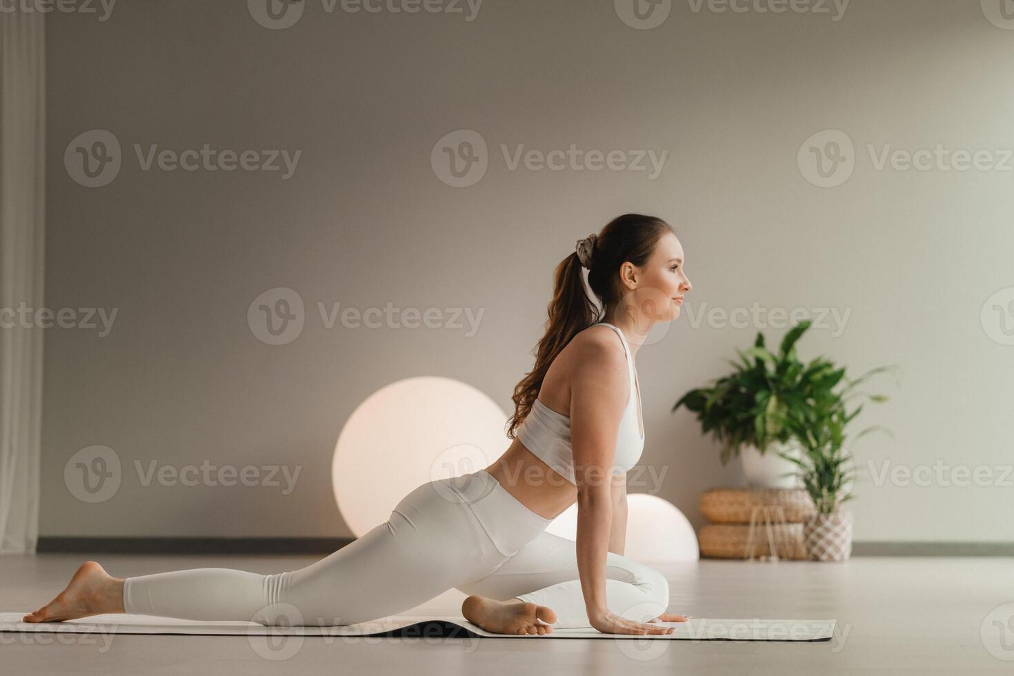 A girl in white clothes does yoga on a mat indoors photo