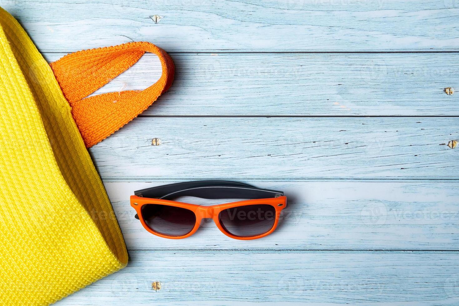 An empty bag with a handle and sunglasses lying on a blue wooden background photo