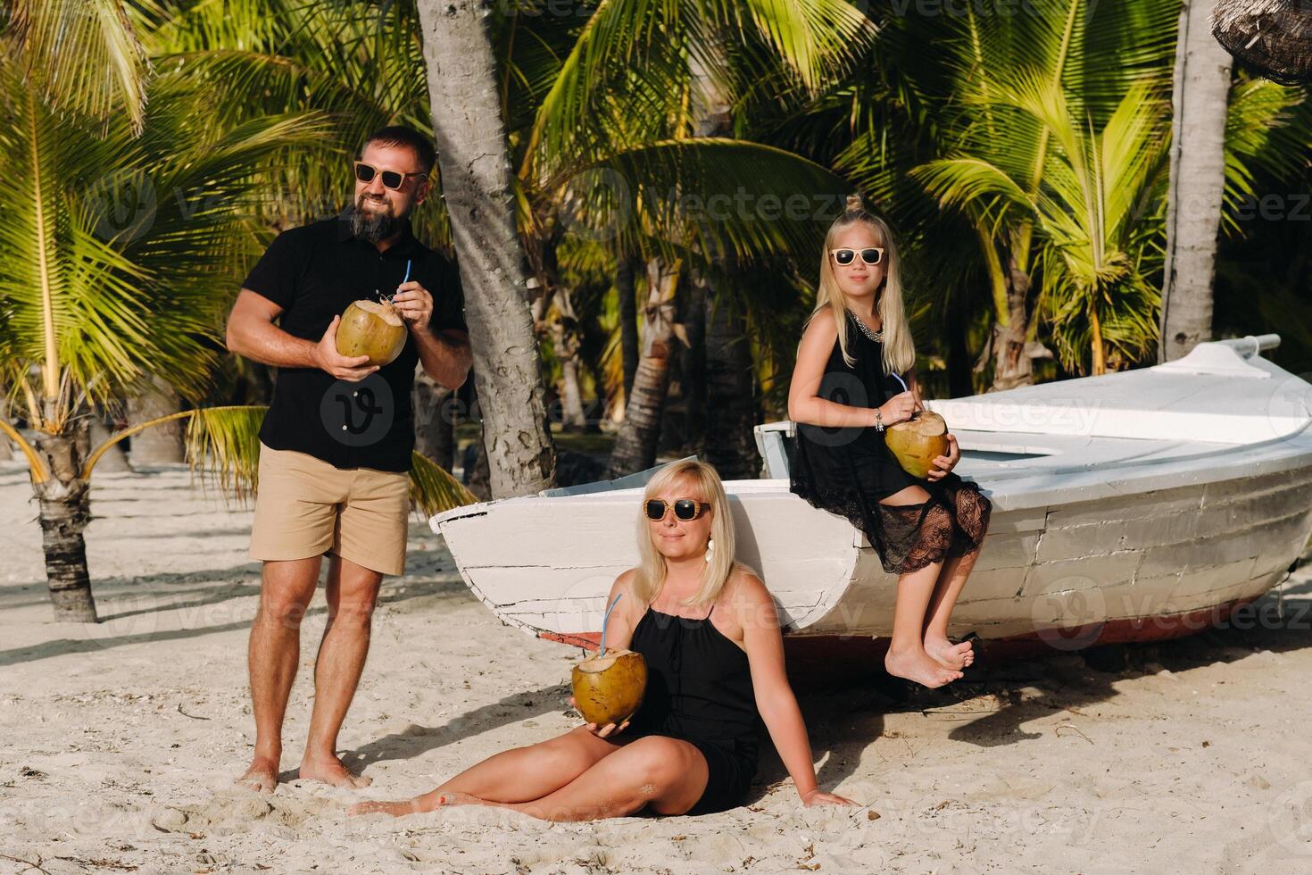 un elegante familia en negro ropa con cocos en su manos en el playa de el isla de mauricio.hermoso familia en el isla de Mauricio en el indio Oceano foto