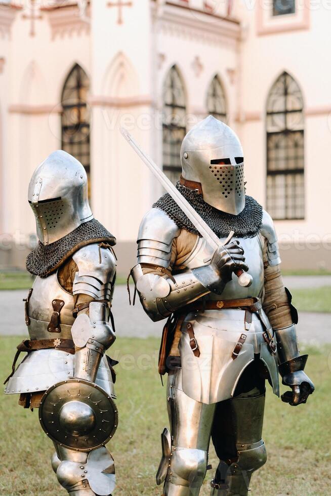 dos caballeros en armadura en el antecedentes de un medieval castillo.a medieval concepto.metálico textura foto