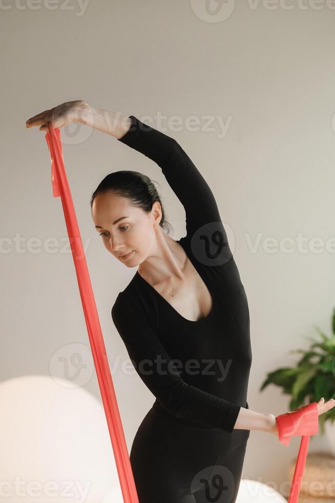 Girl in black doing fitness with red ribbons indoors photo