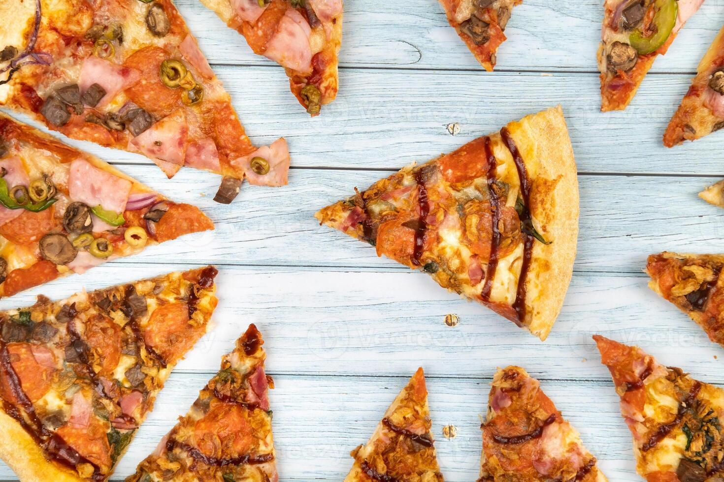 Lots of delicious triangular pizza slices on a blue wooden background photo
