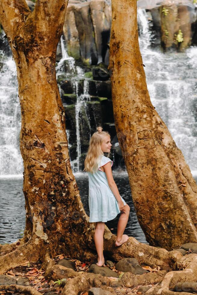 un pequeño niña soportes cerca el Rochester cascada en el isla de mauricio.a cascada en el selva de el tropical isla de Mauricio foto