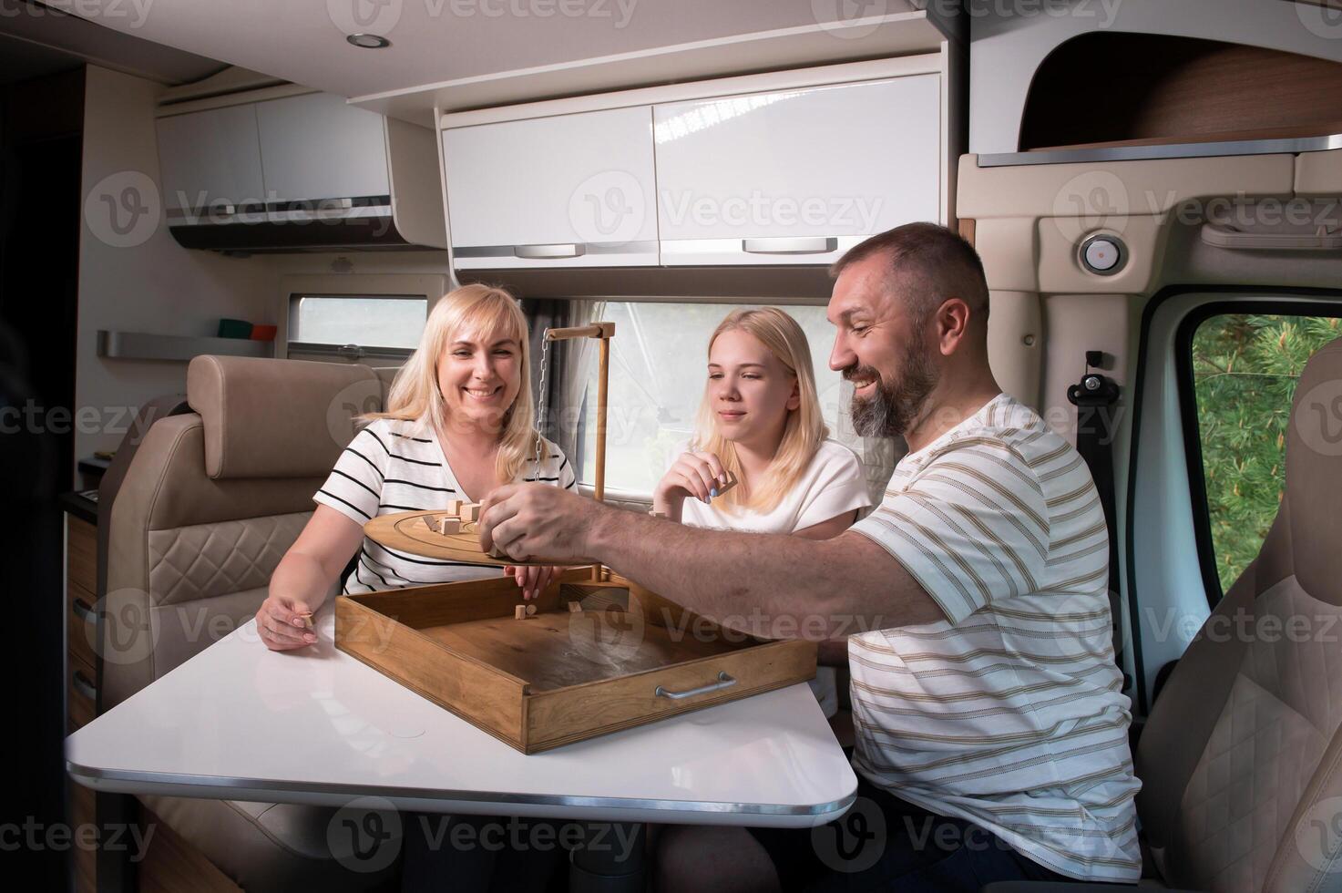 A family of three is playing a board game while sitting in a motorhome photo