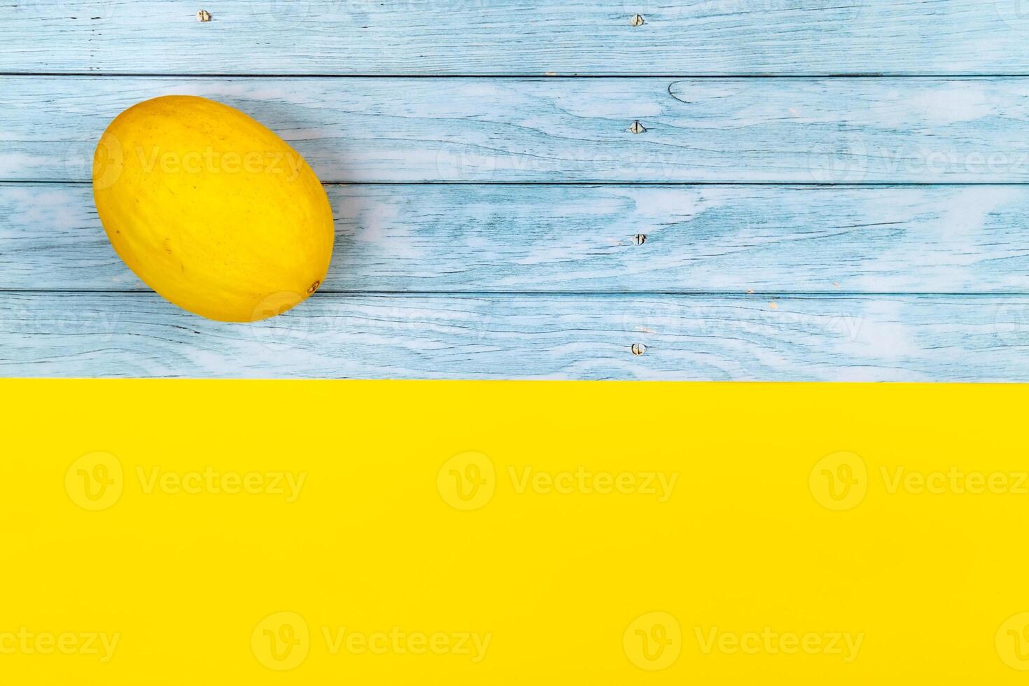 un todo amarillo melón mentiras en un azul de madera antecedentes y un amarillo antecedentes foto