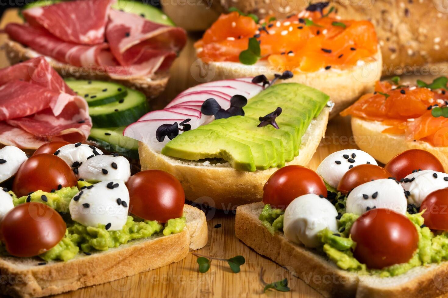 Assorted sandwiches with fish, cheese, meat and vegetables lying on the board photo