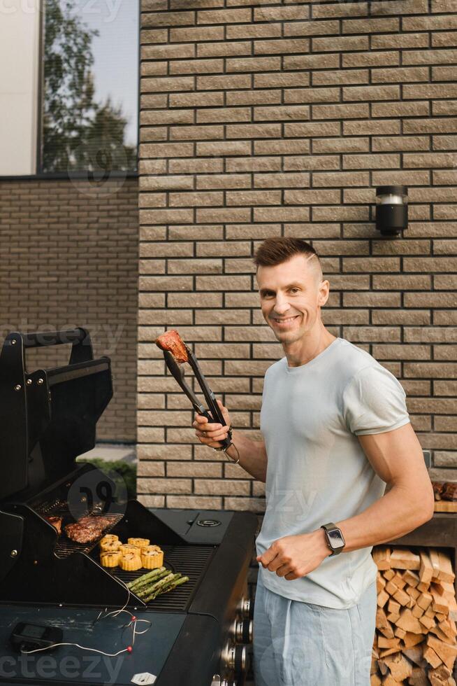 A man on the street is cooking a steak on the grill at a barbecue photo