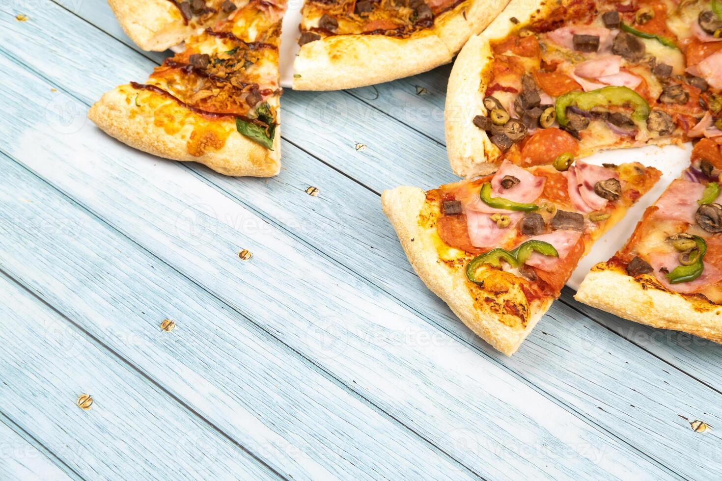 Two different delicious big pizzas on a blue wooden background photo