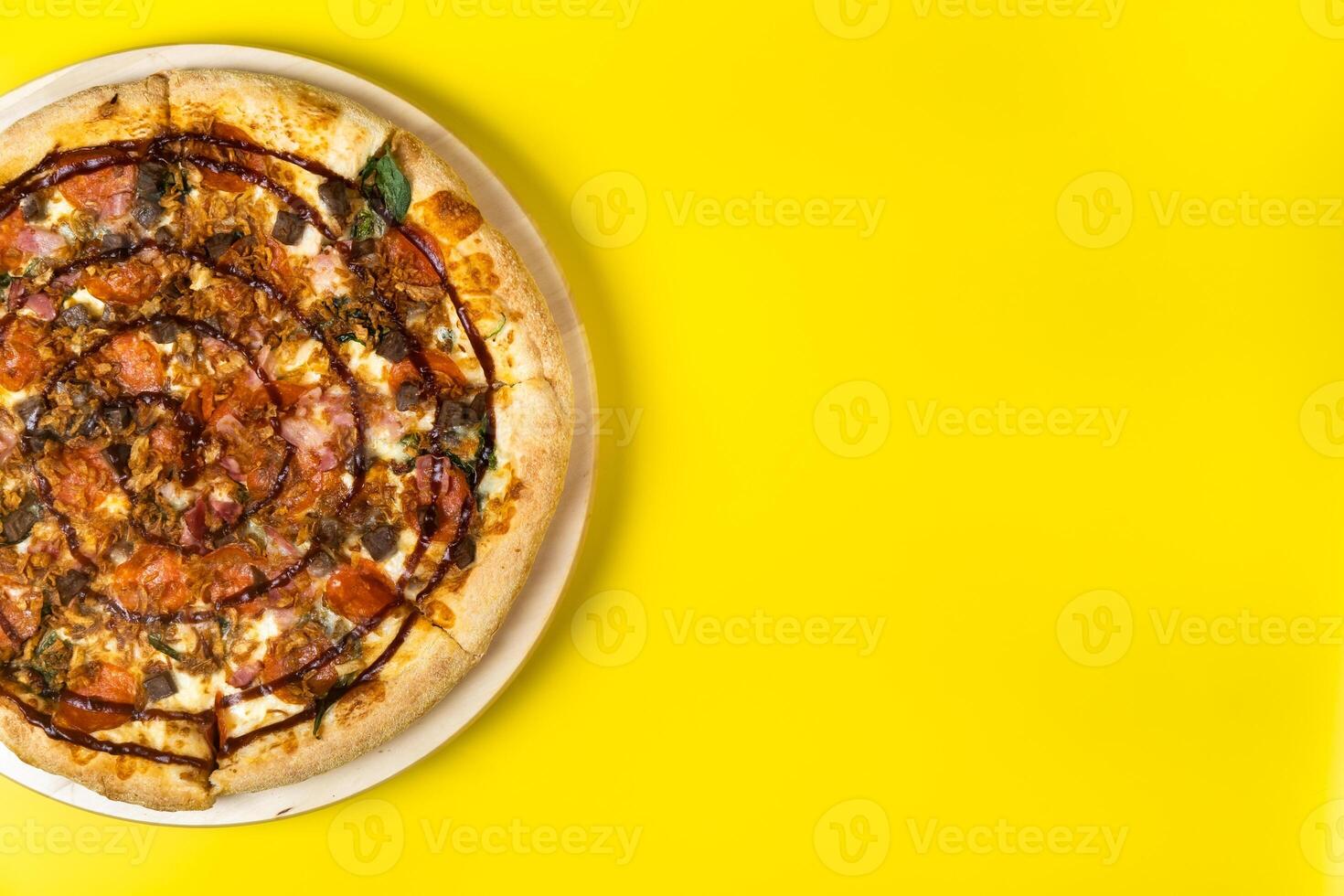 Delicious large pizza with bacon and spinach on a yellow background photo