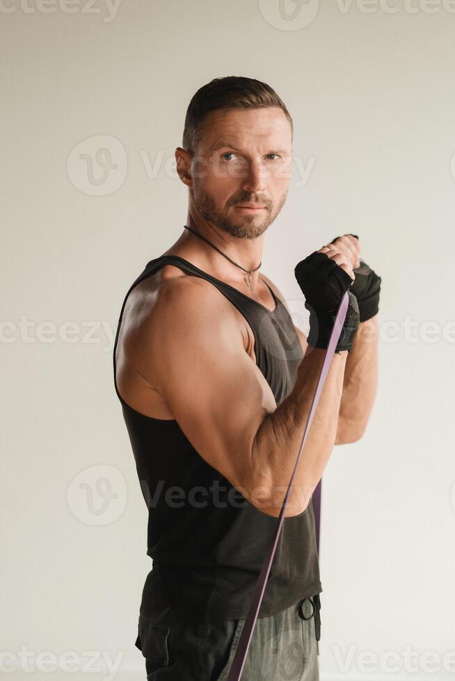 A man in black sportswear is engaged in strength fitness using a rubber loop indoors photo