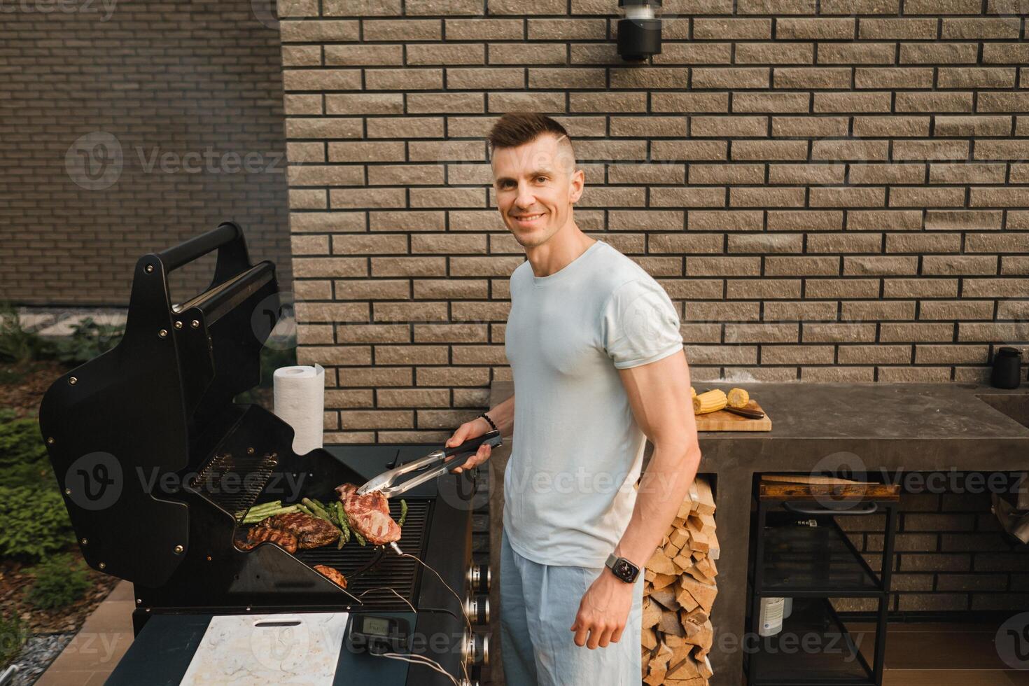 A man on the street is cooking a steak on the grill at a barbecue photo