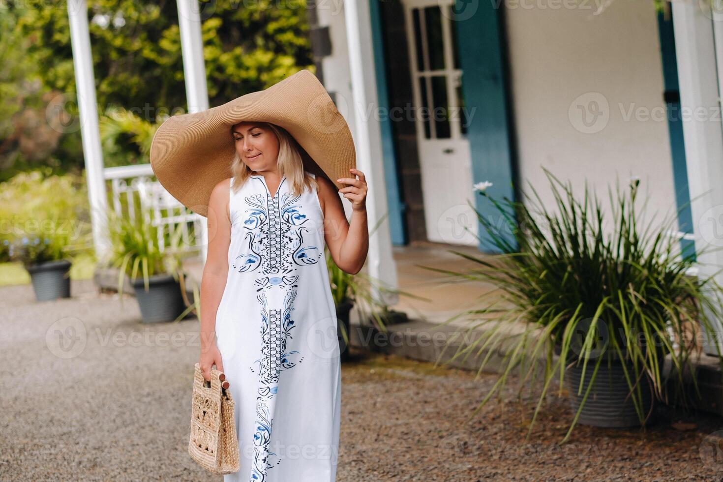 A woman in a big hat with a handbag and a long dress poses on the island of Mauritius. a beautiful girl is resting on the island of Mauritius photo