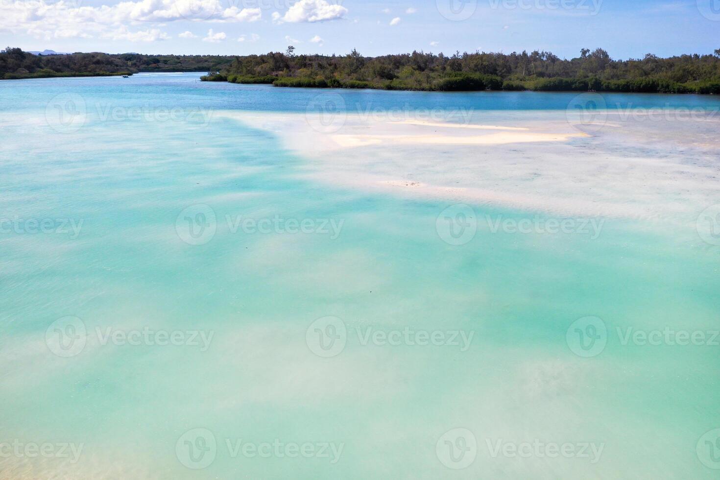 A view from a height of a Tropical beach and waves breaking on a tropical golden sandy beach. The sea waves gently wind along the beautiful sandy beach photo