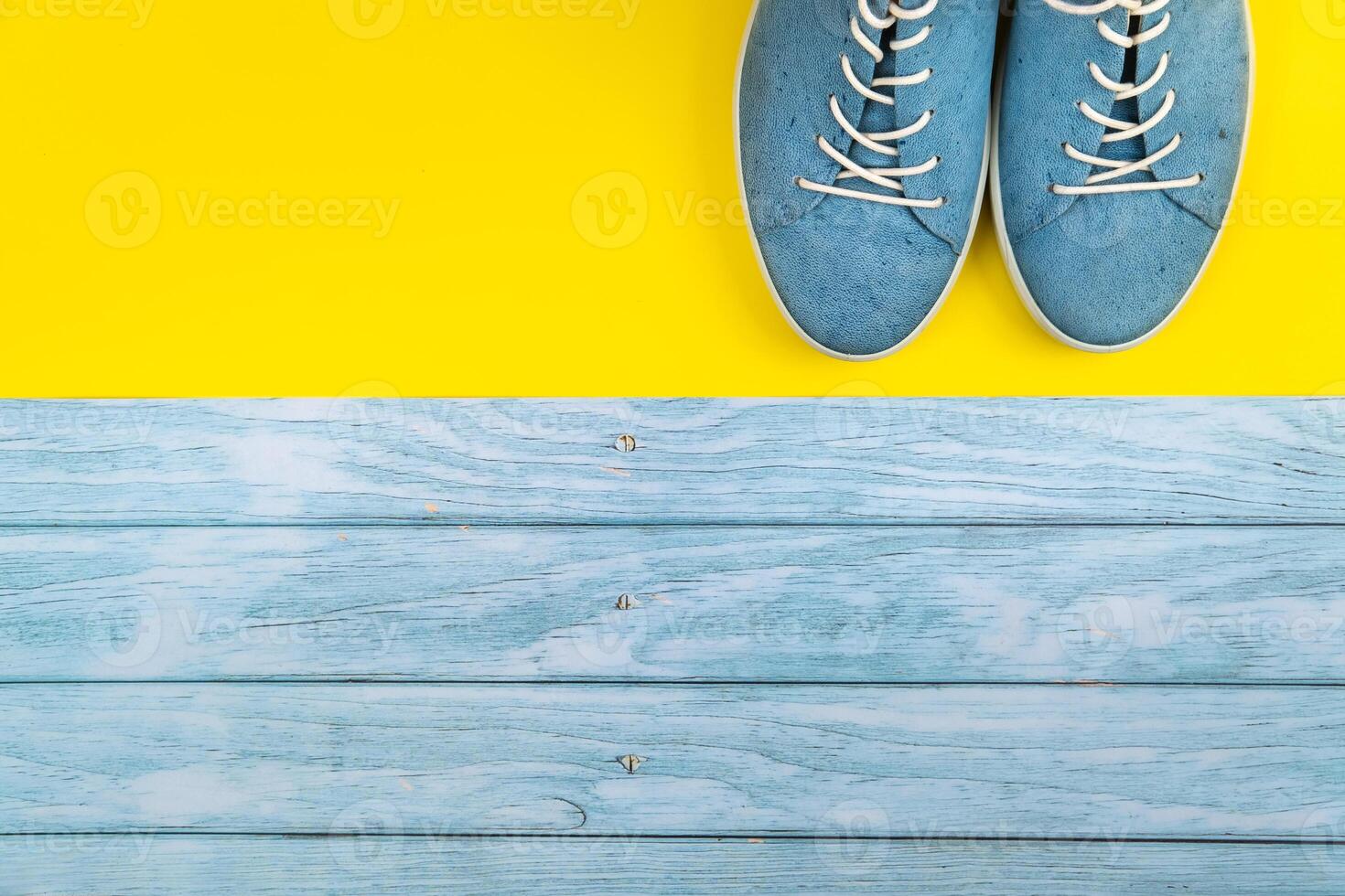 The blue shoes stand on an isolated mixed blue and yellow background photo