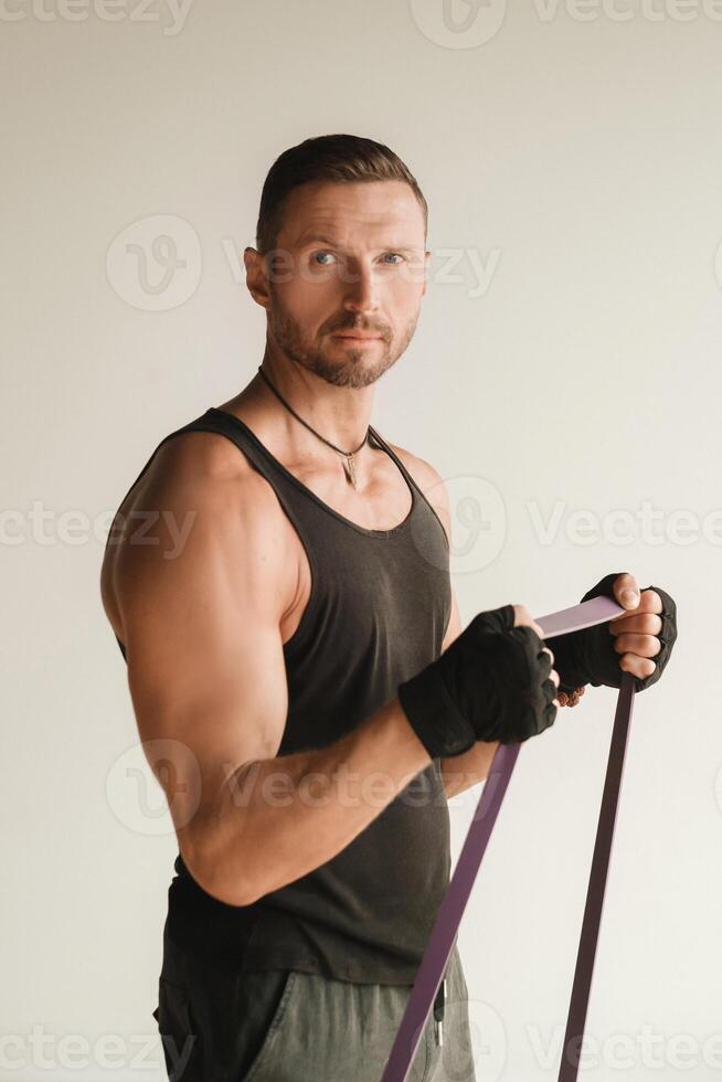 A man in black sportswear is engaged in strength fitness using a rubber loop indoors photo