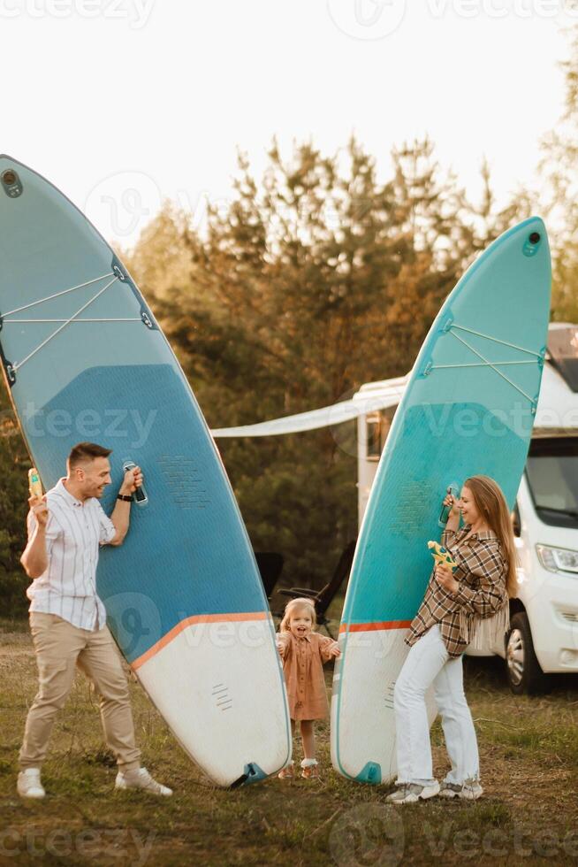 the family is resting next to their mobile home. Dad, mom and daughter play with sup boards and water pistols near a mobile home photo