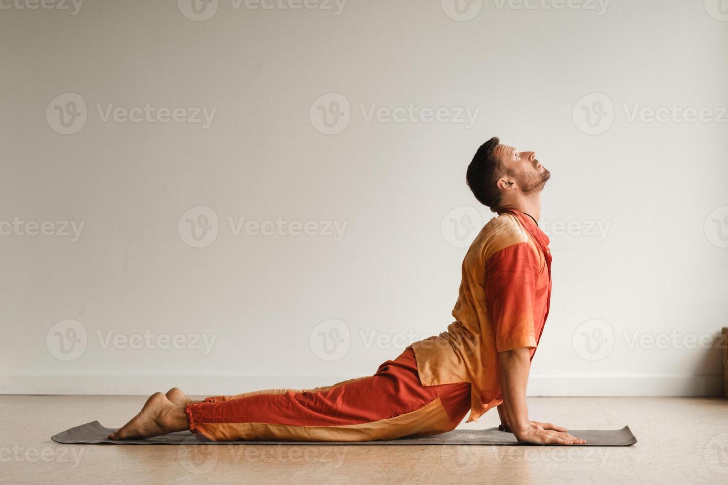 a man in an orange suit does yoga in a fitness room. The concept of health photo