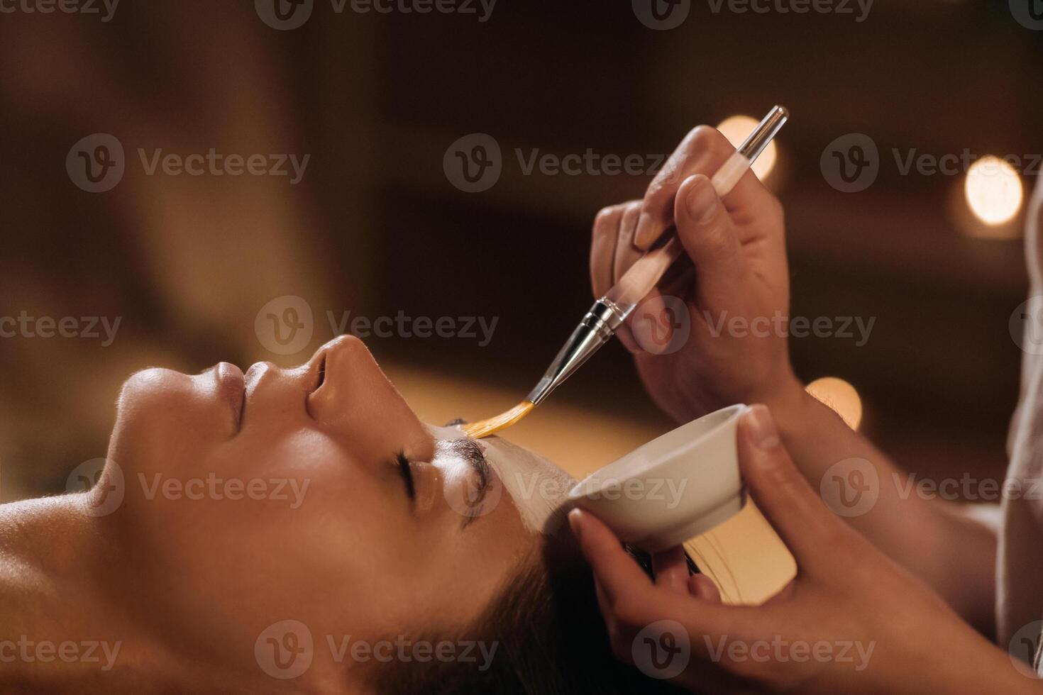 A cosmetologist makes a mask for a woman's face to rejuvenate the skin. Cosmetology photo