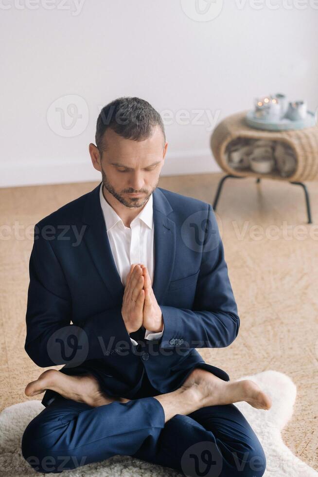 un hombre en un estricto traje lo hace yoga mientras sentado en un aptitud habitación foto