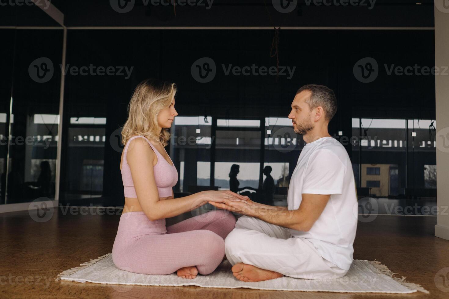 a woman and a man are engaged in pair meditation holding hands in the gym photo