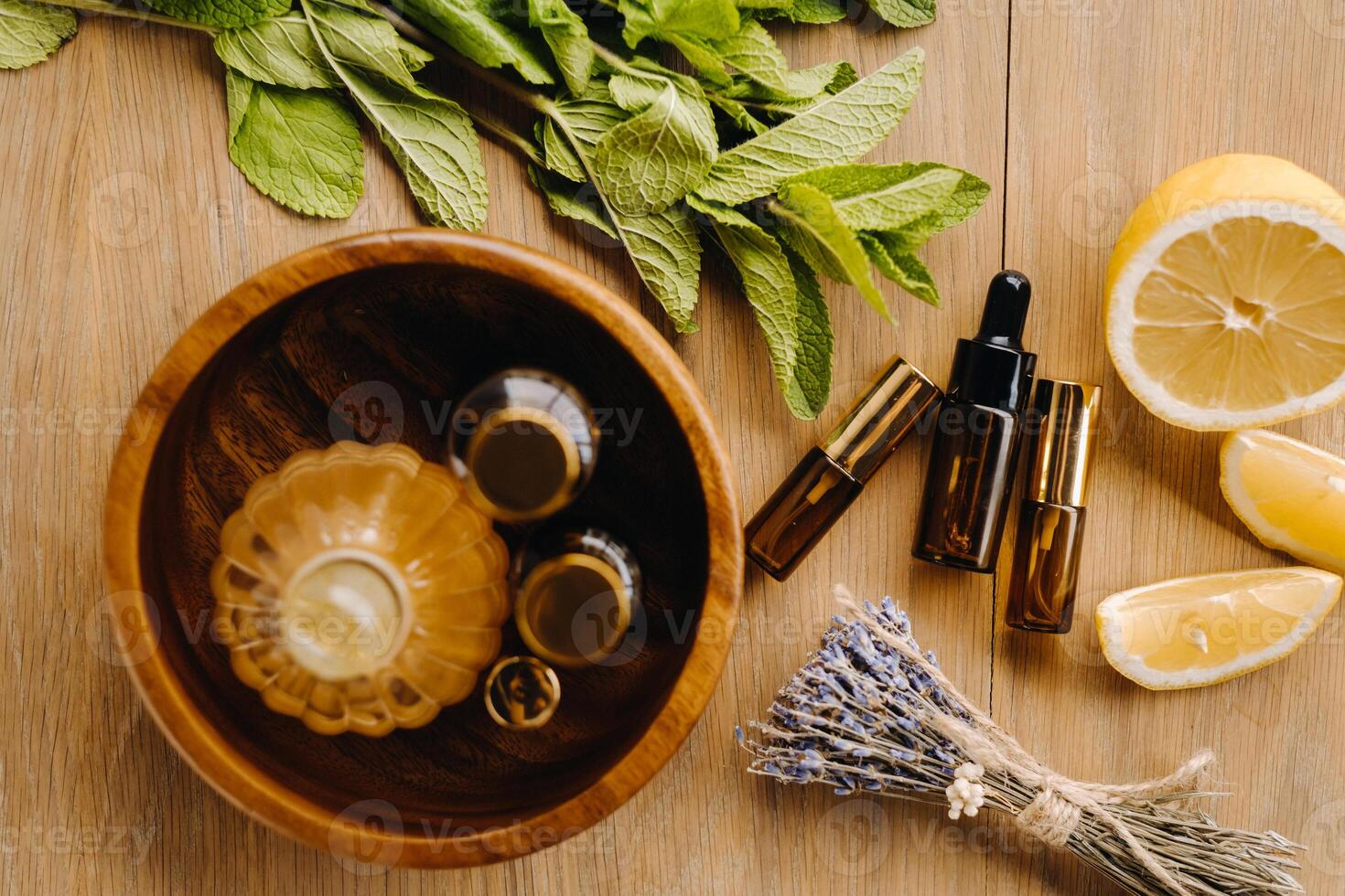Essential oil in bottles with the aroma of lemon, mint and lavender, lying on a wooden surface photo