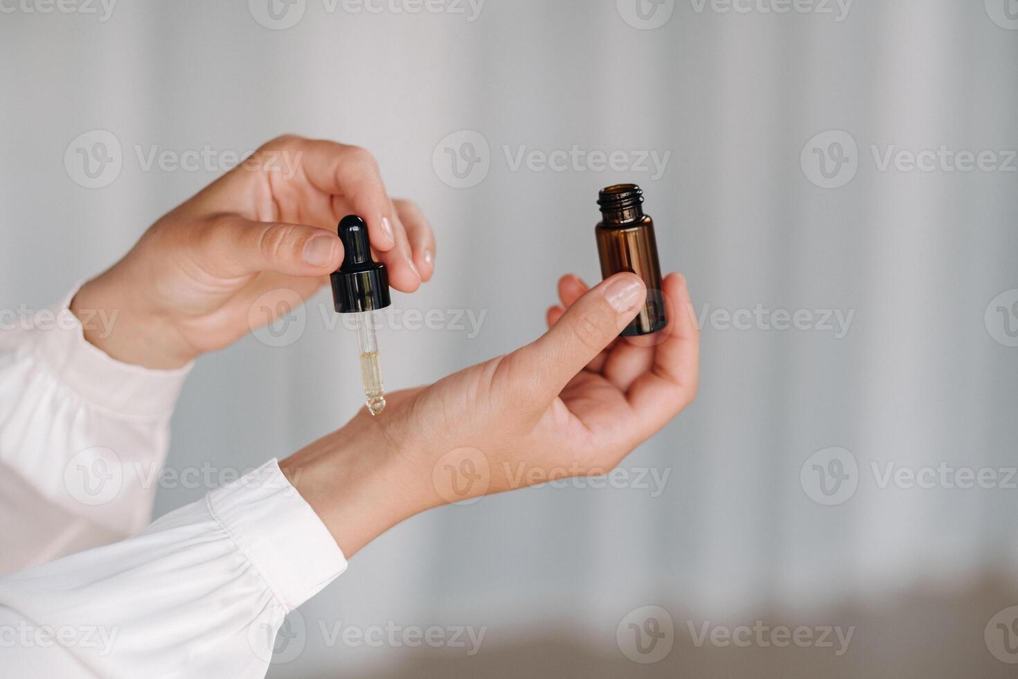Close-up of a Woman's hands applying essential oil on her wrist indoors photo
