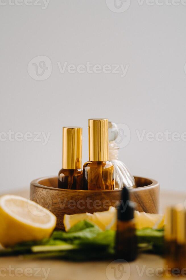 Essential oil in bottles with lemon and mint fragrance lying on a wooden surface photo