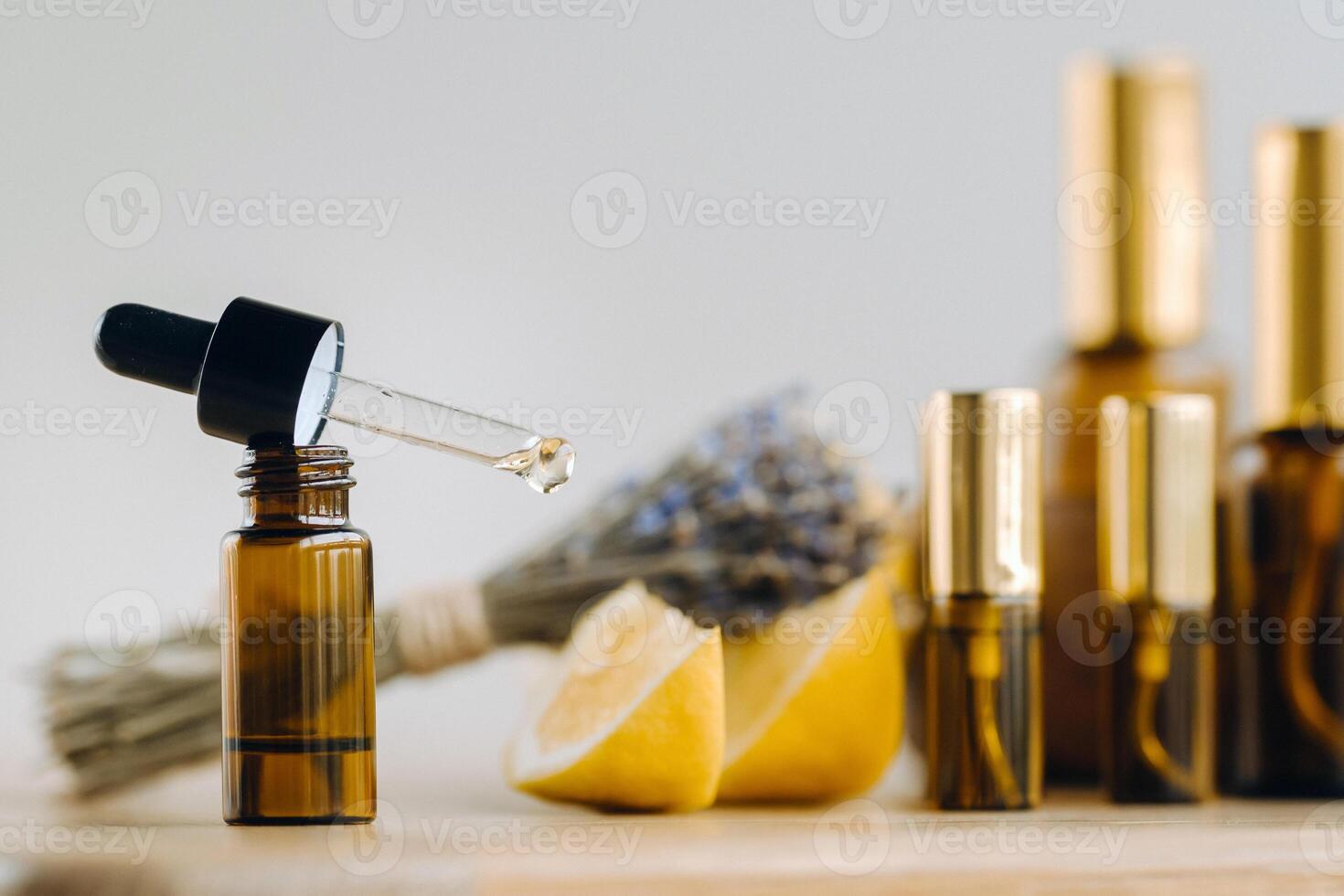 Essential oil in bottles with lemon and lavender fragrance, lying on a wooden surface photo