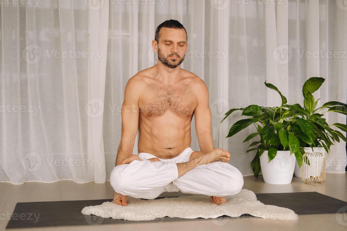 a man with a bare torso does yoga in a fitness room. the concept of a healthy lifestyle photo