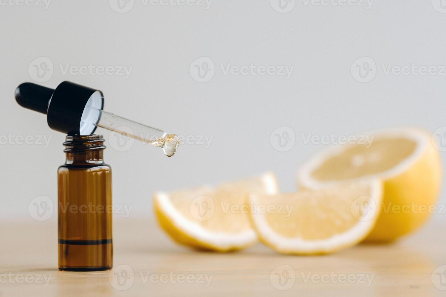 Essential oil in one bottle and lemon lying on the surface photo