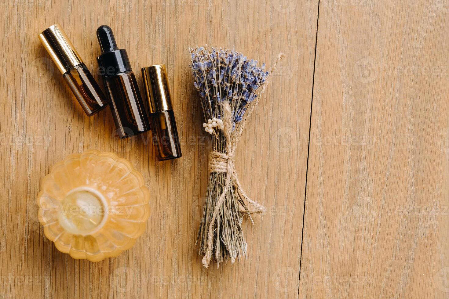 Essential oil in one bottle and dried lavender standing on the surface photo