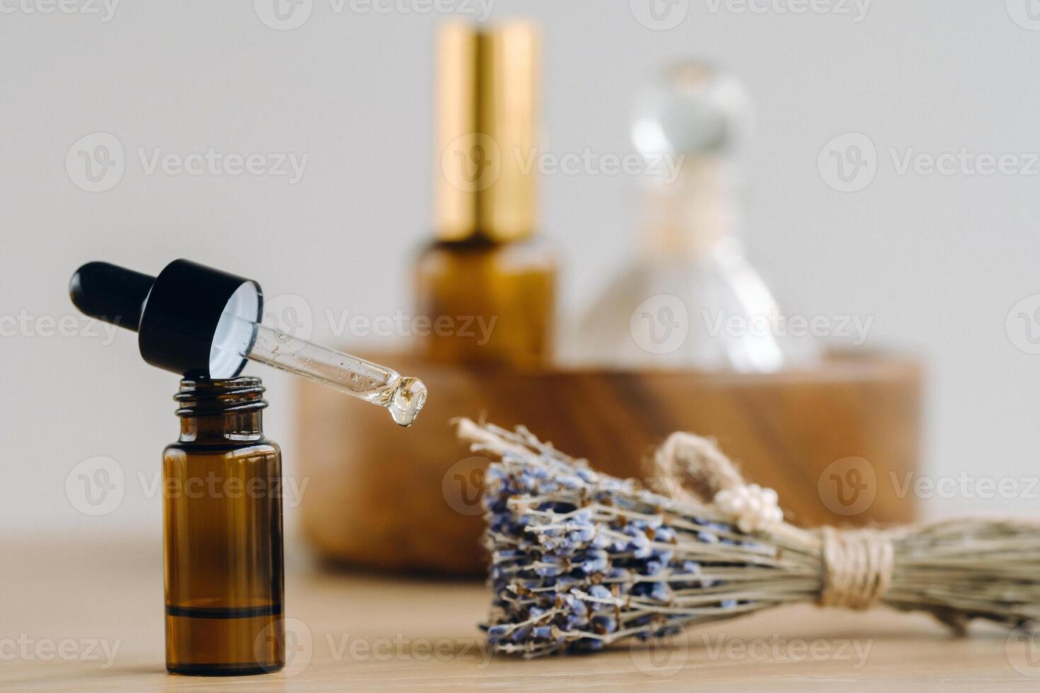 Essential oil in one bottle and dried lavender standing on the surface photo